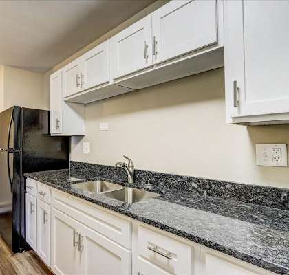 a kitchen with white cabinets and a black refrigerator