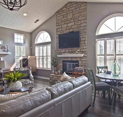 A living room with a grey couch and a stone fireplace.