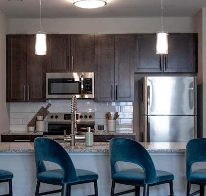 a kitchen with blue chairs and a counter top at The Century at Purdue Research Park-Student, Indiana