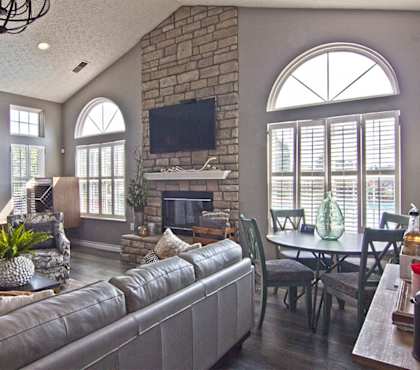 A living room with a grey couch and a stone fireplace.