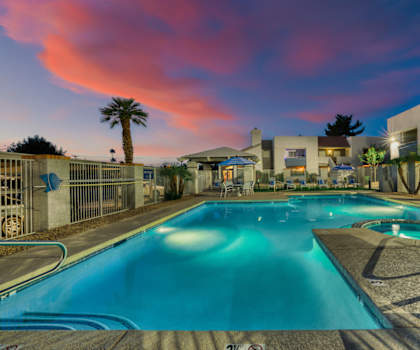 a swimming pool with a colorful sunset in the background