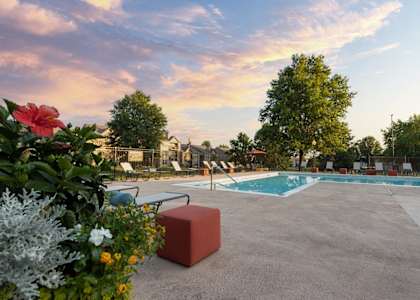 The Lakes pool area, with lounge chairs, a table, and chairs surrounding the clear blue pool.
