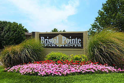 A sign for Bristol Pointe Farms with flowers in the foreground.