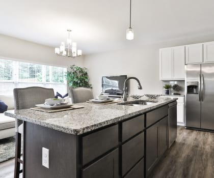 an open kitchen with granite counter tops and stainless steel refrigerator