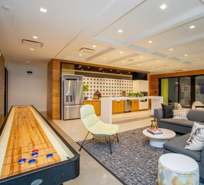 Clubroom View including common space kitchen area, seating area, and shuffleboard table  at Grand Flats, St. Louis, MO, 63104