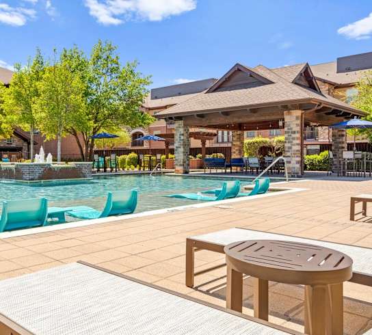 a swimming pool with lounge chairs and a table