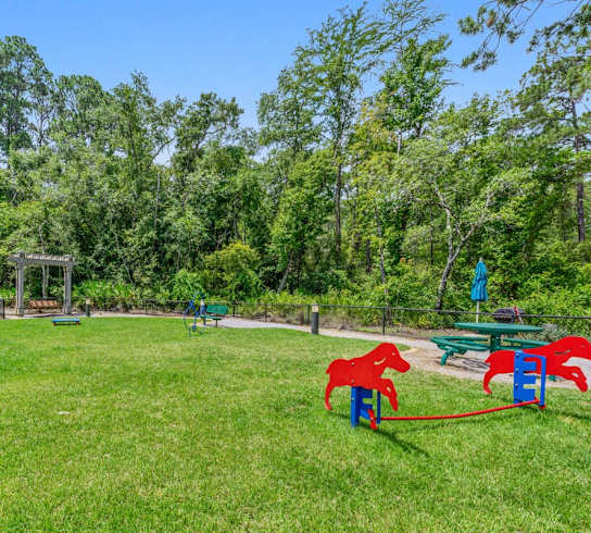 A playground with a red slide and a red horse.