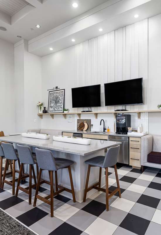 a dining area with a table and chairs and two televisions on the wall