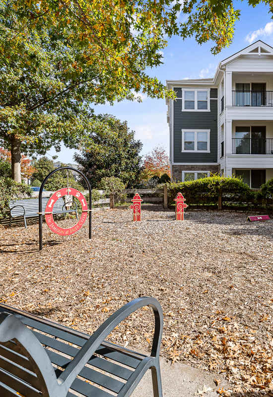 a park with a bench and a basketball hoop in front of an apartment building