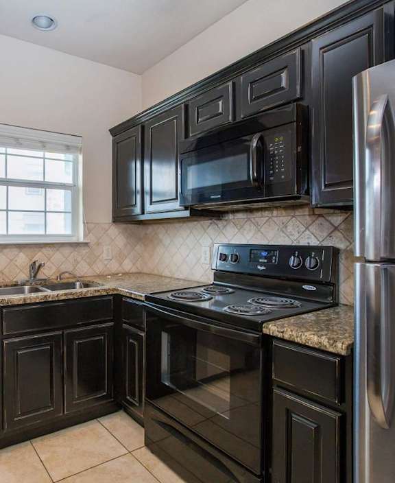 A kitchen with black cabinets and stainless steel appliances. at Logan Ridge Apartments, Apartments, San Marcos, TX