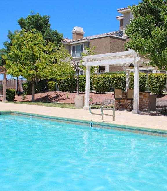 A pool with a white pergola and trees in the background at Avalon at Seven Hills Apartments, Henderson, 91790