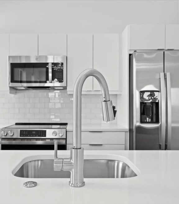 a white kitchen with stainless steel appliances and a sink