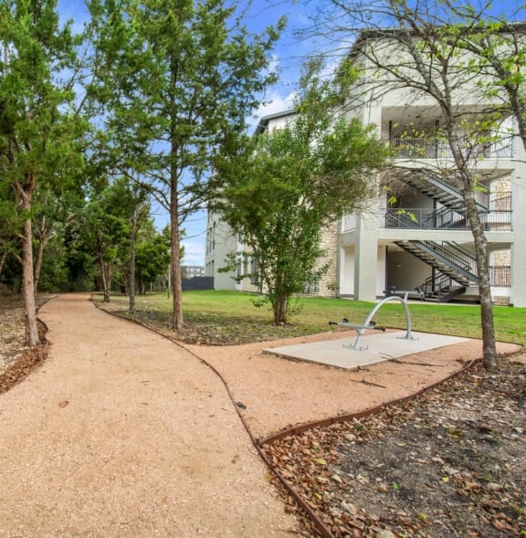 a path with trees and a building in the background at Radius on Grove, Austin, Texas