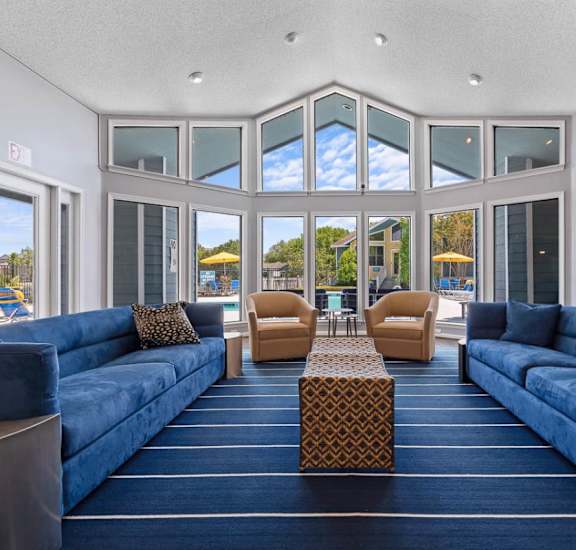 A large room with blue couches and a table in the middle.