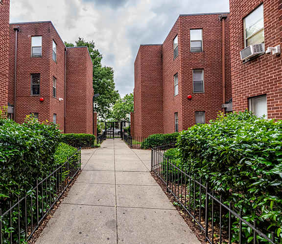 a walkway between two brick apartment buildings with a sidewalk