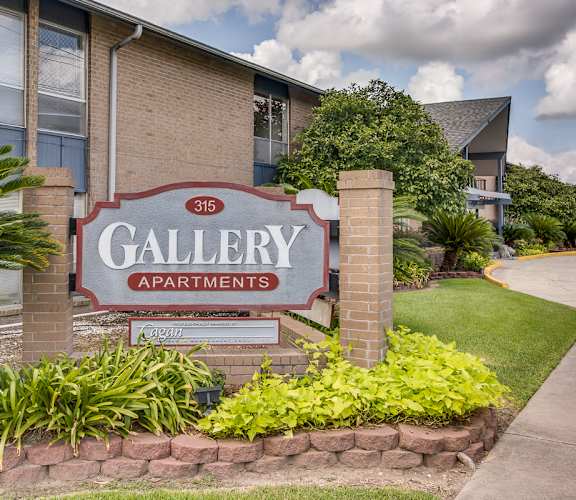 A sign for Gallery Apartments is in front of a building.