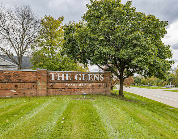 The Glens Apartments sign is on a brick wall.