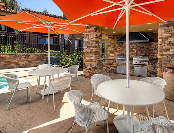 A patio with a table and chairs under an orange umbrella.