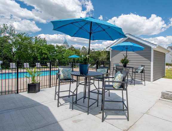 A blue umbrella is on a table outside a house.