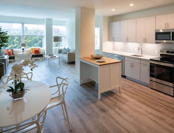 a kitchen and dining room with grey cabinets and stainless steel appliances at Sinclaire on Seminary, Alexandria, VA 22311