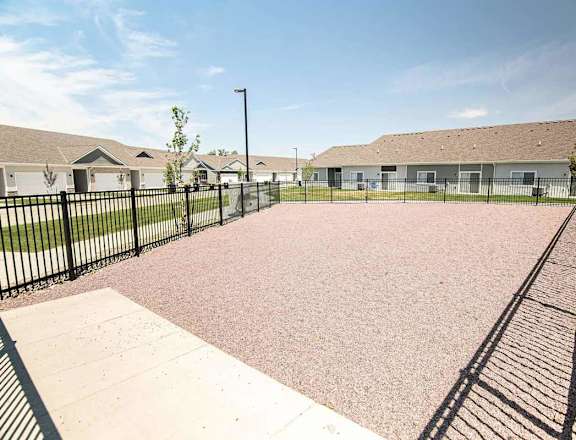 A playground with a black fence and a pink surface.