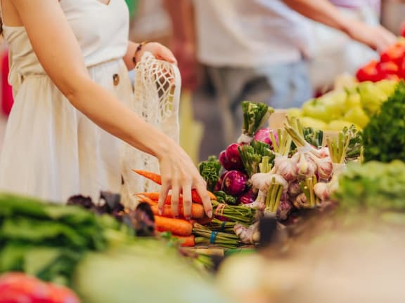 woman picking up carrots and farmers market