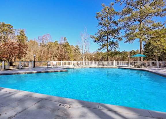 Swimming pool with lounge chairs and a table with an umbrella at our apartments in Dunwoody.