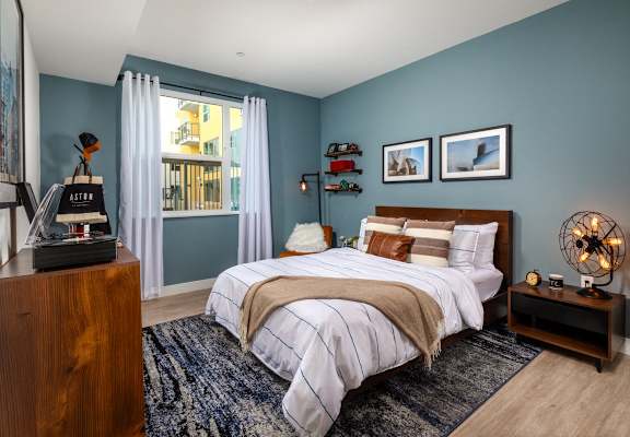 a bedroom with blue walls and a bed at Aston at Gateway Apartments, El Monte, California