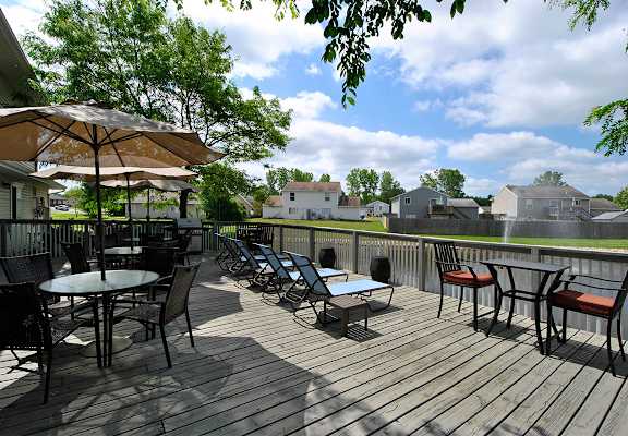 A wooden deck with chairs and umbrellas overlooking a residential area.