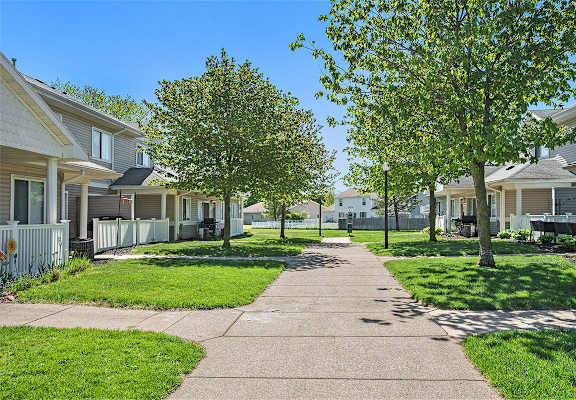 A residential street with houses on both sides and a sidewalk in the middle.
