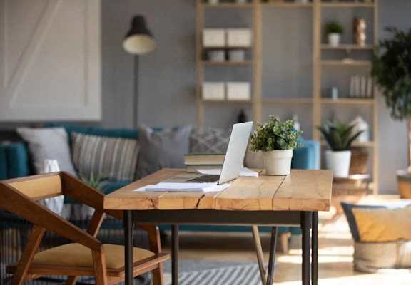 A wooden table with a laptop and a plant on it.