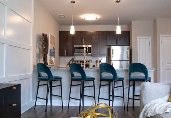 a kitchen with a breakfast bar and stools at The Century at Purdue Research Park-Student, West Lafayette, IN 47906