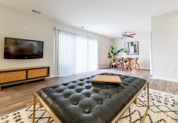 A black tufted bench is in the middle of a white and black patterned rug.