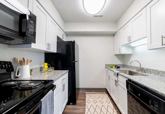A kitchen with black appliances and white cabinets.