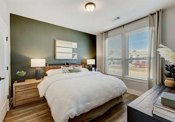 a bedroom with a large bed and two large windows