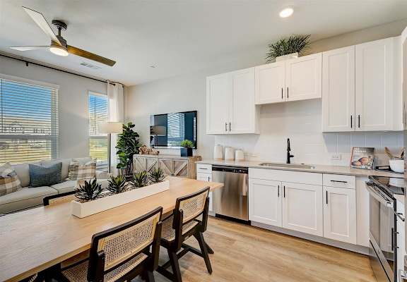 a kitchen and living room with white cabinets and a wooden table