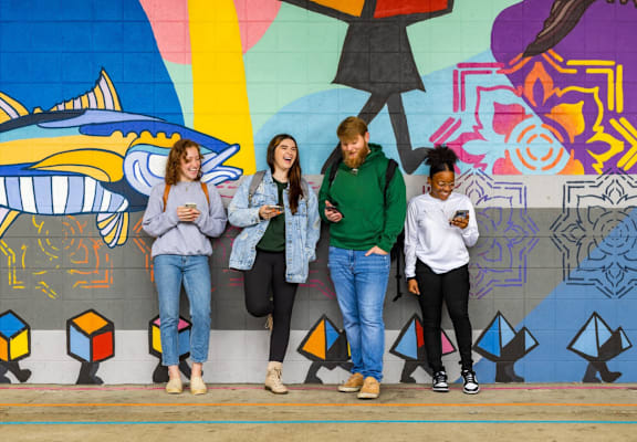Four people standing in front of a colorful wall.