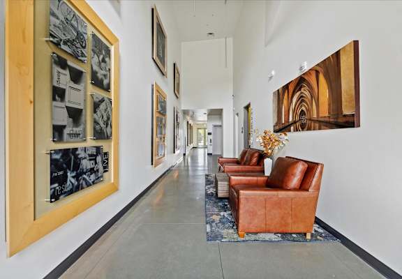 A hallway with a row of chairs and pictures on the wall.