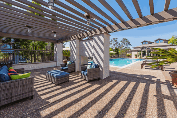 a covered patio with chairs and a pool
