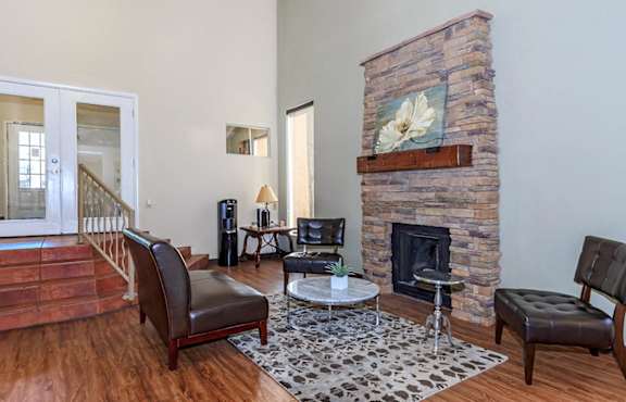 A living room with a stone fireplace and a painting of a white flower above it.