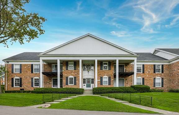 A brick house with a white roof and a green lawn in front at Glens of Bloomfield Apartments, Michigan, 48301
