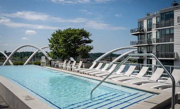 A pool with chairs and a building in the background. at Dock 79, District of Columbia, 20003