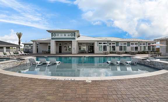 a large pool with chairs in front of a building