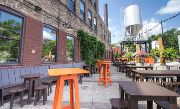 A patio with tables and chairs is set up outside a brick building.