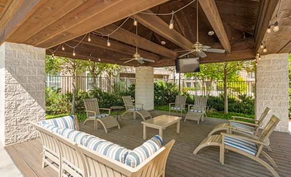 a covered patio with chairs and a tv