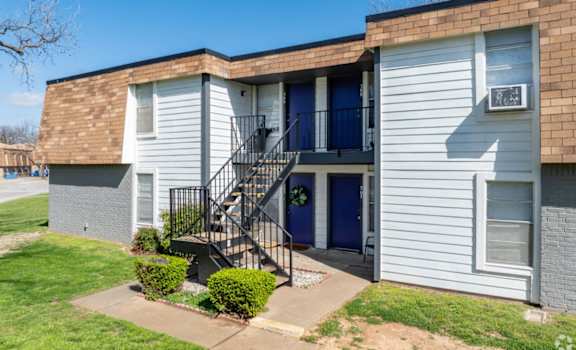 A small apartment building with a blue door and a black metal staircase.