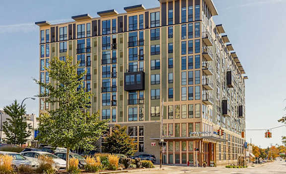 A large, modern building with many windows is situated on a street corner.