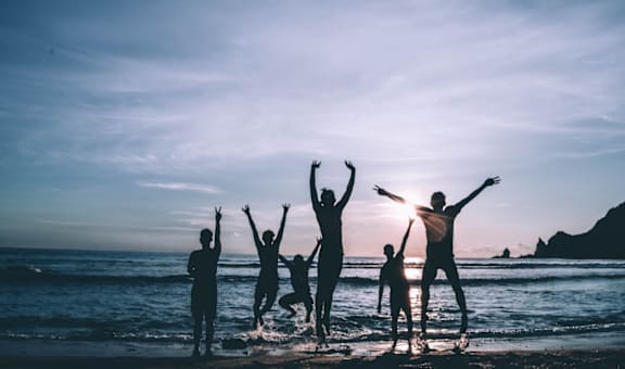 a group of people standing on the beach with their hands in the air