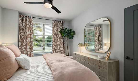 a bedroom with a bed and a mirror and a window