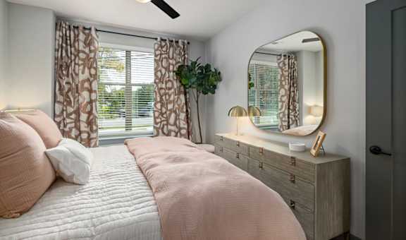 a bedroom with a bed and a mirror and a window